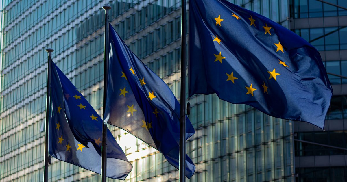 Flagi Unii Europejskiej przed budynkiem Komisji Europejskiej w Brukseli - unijny AI Act dla firm w UK